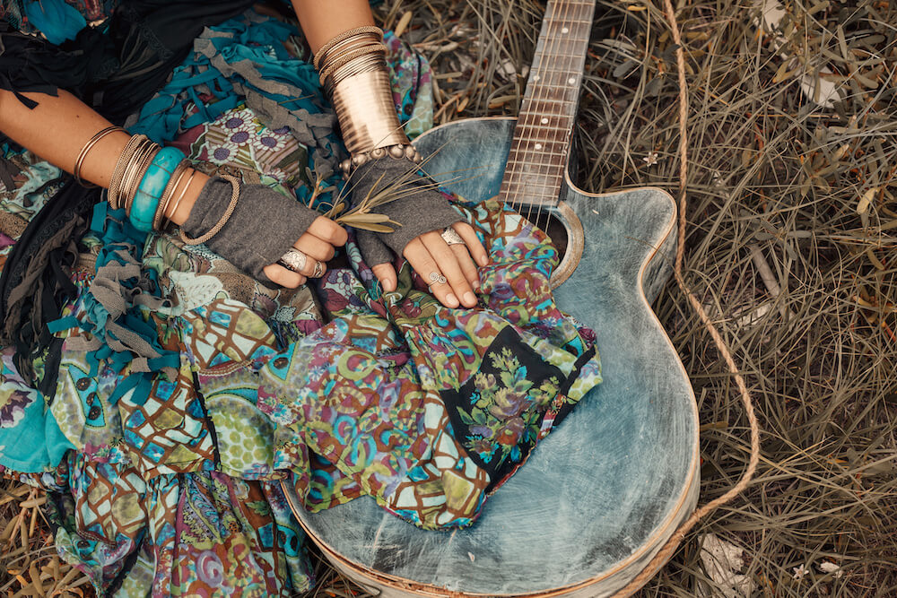 close up photo of gypsy girl hands with guitar on green grass